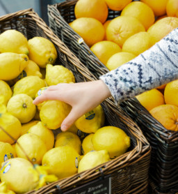 Person testing lemons in a Billa Corso supermarket